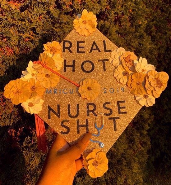 A sparkling gold graduation cap held in hand, boldly stating 'REAL HOT NURSE SH*T' in black letters