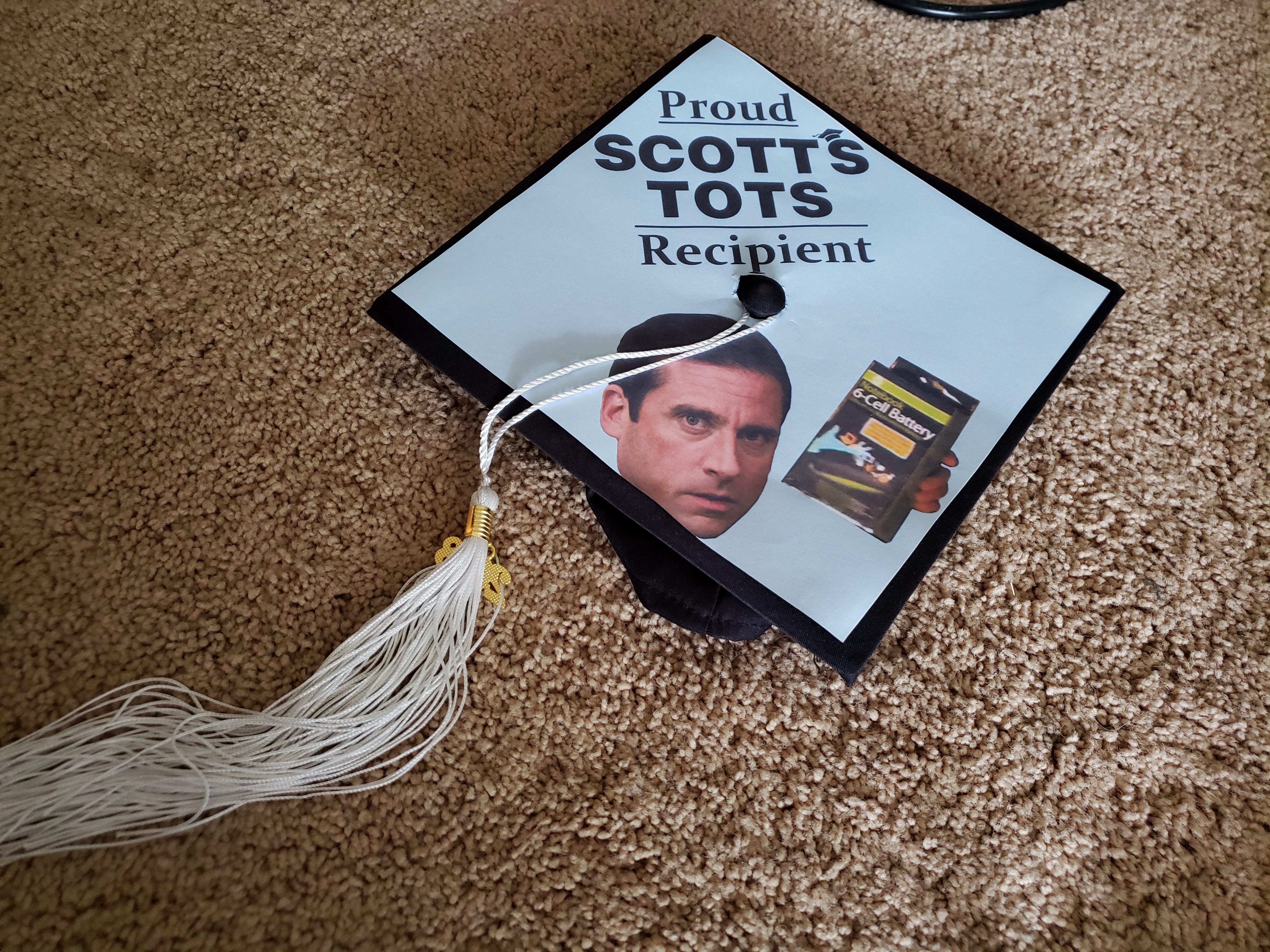 Graduation cap with Michael Scott's face and the words proud scott's tots recipient