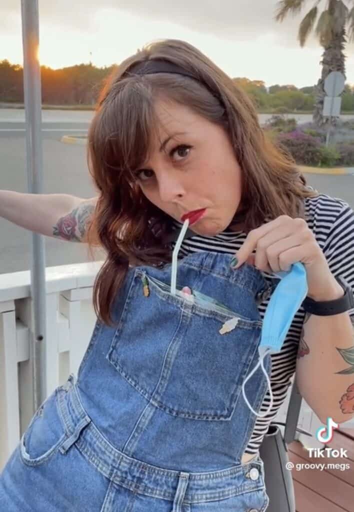 girl drinking out of overalls pocket with straw