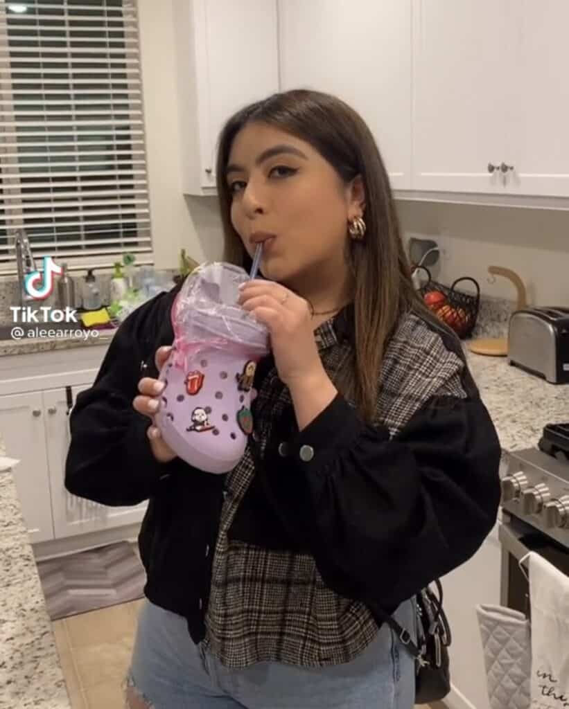 girl drinking from purple croc shoe