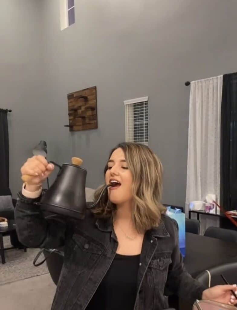 girl drinking from black tea kettle