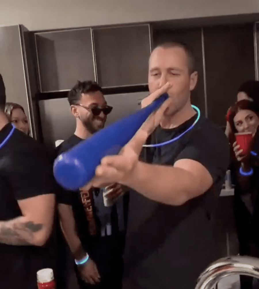 guy drinking from the end of a blue plastic baseball bat at anything but cup party