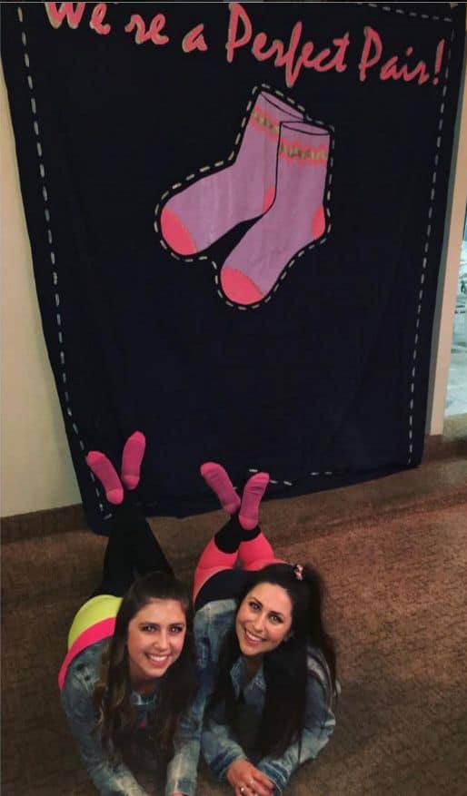 two sorority sisters laying on the floor wearing matching socks