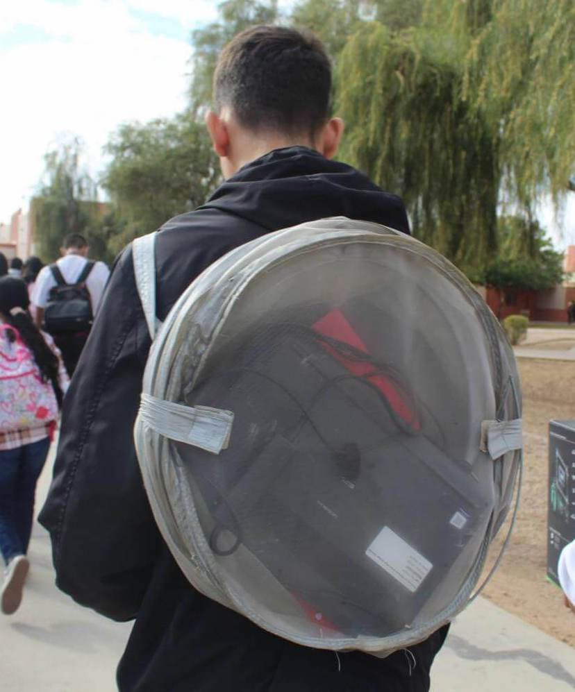 student carrying a laundry hamper on his back with items inside