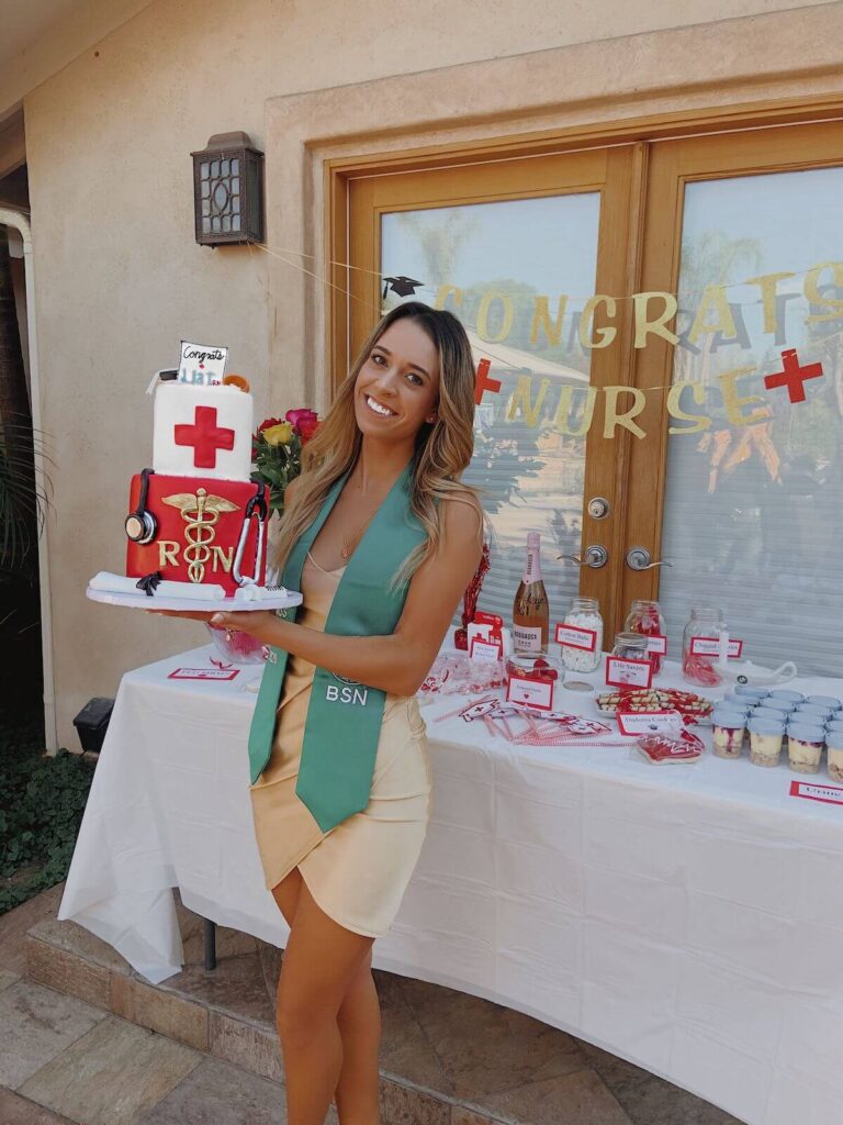 graduate standing in front of a dessert table holding a nursing themed cake at her graduation party