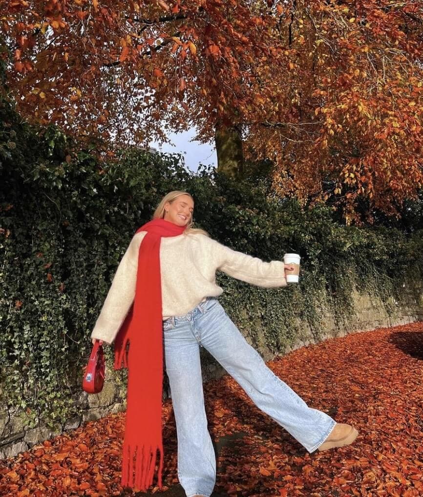 person wearing jeans, a sweater, and a red scarf