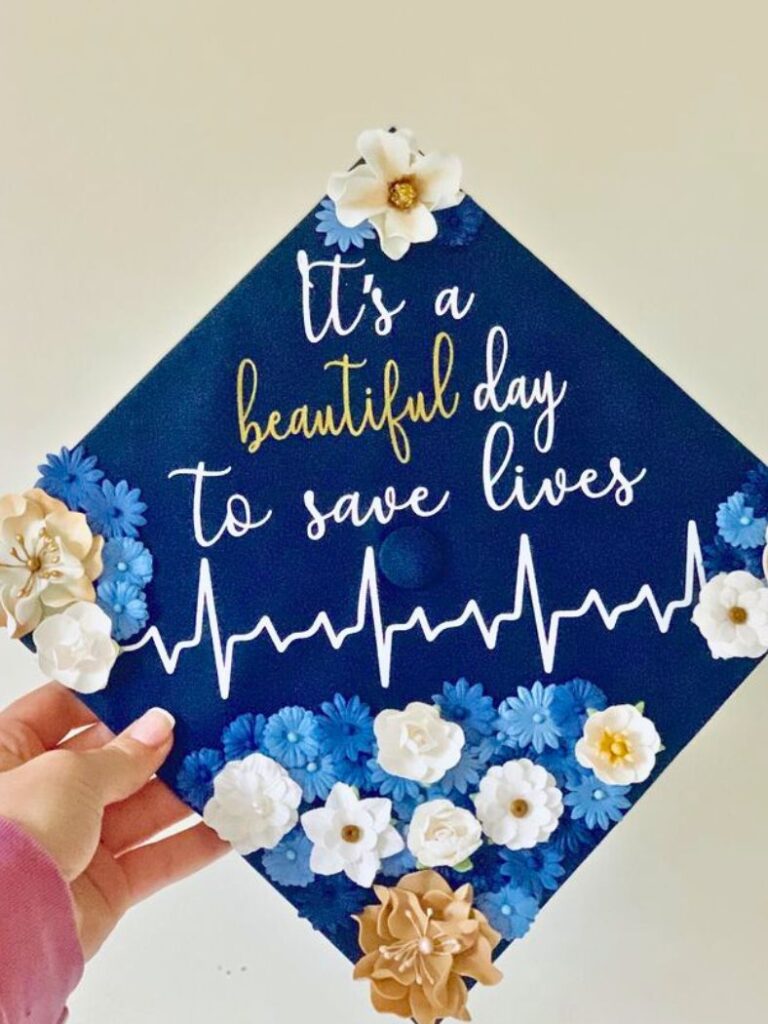 A navy blue graduation cap with the inspirational quote 'It's a beautiful day to save lives' in elegant cursive white lettering, accompanied by an EKG heartbeat line.